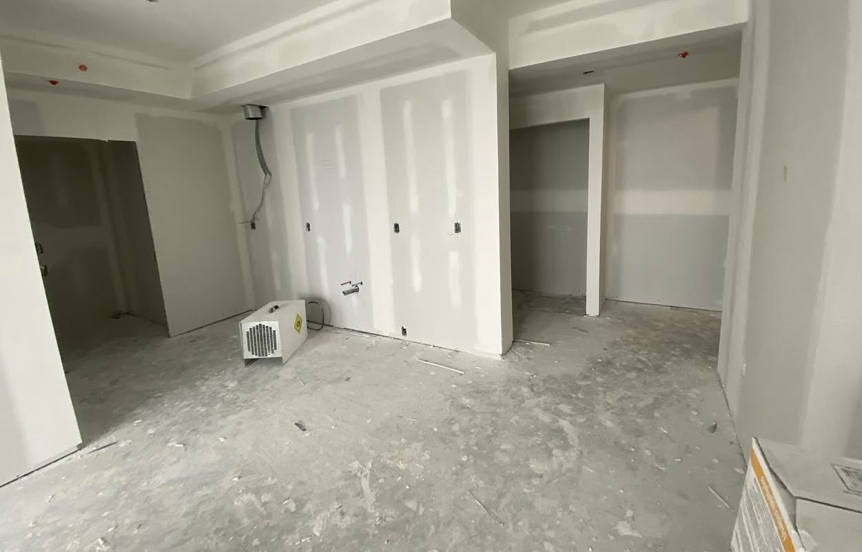Painter rolling fresh white paint on a Level 5 drywall finish in a North York home